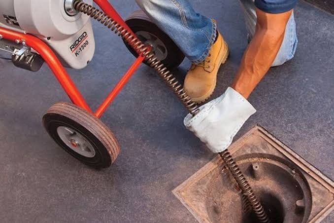 Máquina rotativa com cabo de aço desentupindo ralo de piso